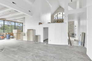 Unfurnished living room featuring high vaulted ceiling and beam ceiling