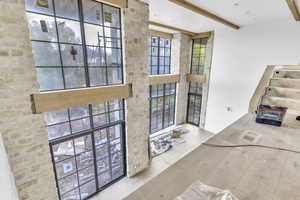 Doorway featuring healthy amount of natural light, wood finished floors, beam ceiling, and a towering ceiling
