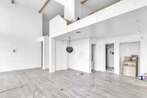 Unfurnished living room featuring light wood-style flooring and a high ceiling