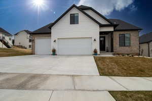 View of front of home featuring driveway, brick siding, a garage, and a front yard