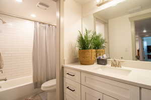 Bathroom featuring shower / bath combo, visible vents, toilet, and vanity