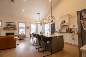 Kitchen with a sink, a kitchen bar, a glass covered fireplace, light wood-style flooring, and decorative backsplash