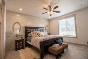 Bedroom with a decorative wall, light carpet, baseboards, and a textured ceiling