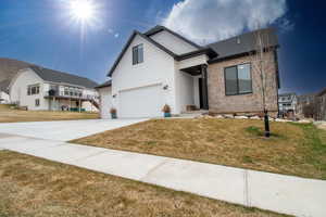 View of front facade with brick siding, concrete driveway, and a front yard