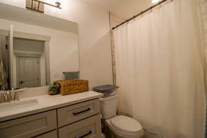 Full bath featuring curtained shower, toilet, and vanity