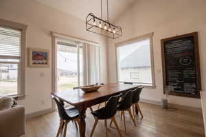 Dining area with baseboards, light wood-style flooring, and vaulted ceiling