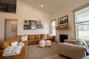 Living area featuring a wealth of natural light, high vaulted ceiling, recessed lighting, and a glass covered fireplace