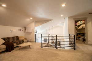 Interior space with carpet flooring, an upstairs landing, and lofted ceiling