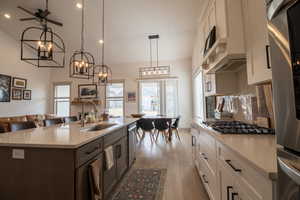 Kitchen with light countertops, light wood finished floors, appliances with stainless steel finishes, a sink, and open floor plan