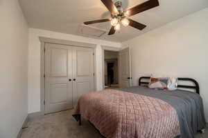 Carpeted bedroom featuring a closet, baseboards, attic access, and ceiling fan