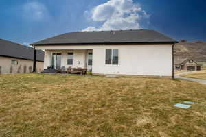 Back of property featuring a lawn and stucco siding