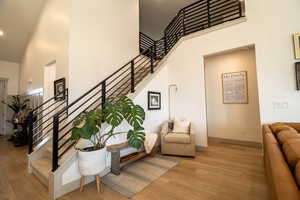 Stairs featuring baseboards, a towering ceiling, and wood finished floors