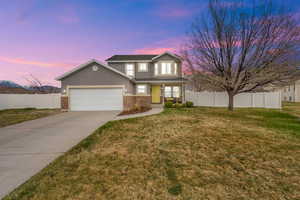Traditional-style home featuring driveway, stucco siding, fence, and 2-car garage