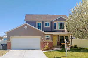 View of front of house featuring stucco siding, a front yard, fence, brick siding, and concrete driveway