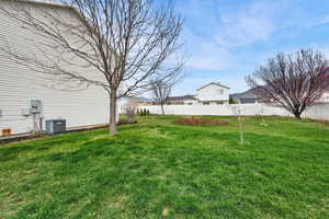 View of yard with central AC and fence