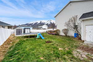 View of yard with a fenced backyard, an outbuilding, a mountain view, and a storage shed