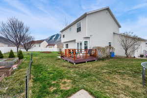 Back of house featuring fence, a deck with mountain view, a vegetable garden and french doors