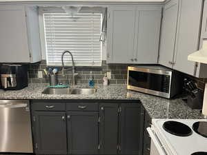 Kitchen with backsplash, a sink, exhaust hood, and appliances with stainless steel finishes