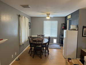 Dining room with light wood-type flooring, a ceiling fan, baseboards, and visible vents