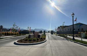 View of street featuring a mountain view, sidewalks, street lights, and curbs