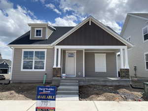 View of front of house featuring board and batten siding, roof with shingles, and covered porch