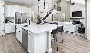 Kitchen featuring a ceiling fan, appliances with stainless steel finishes, a sink, light wood-style floors, and open floor plan