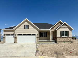 Craftsman-style home with an attached garage, roof with shingles, stone siding, and concrete driveway