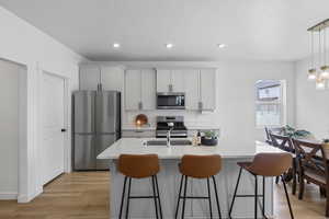 Kitchen with light wood finished floors, light countertops, a kitchen breakfast bar, and appliances with stainless steel finishes