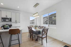 Dining space with light wood finished floors, baseboards, recessed lighting, and an inviting chandelier