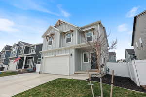View of front of property featuring fence, a garage, concrete driveway, board and batten siding, and a residential view