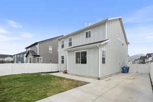 Rear view of house with a fenced backyard, a patio, board and batten siding, and a yard