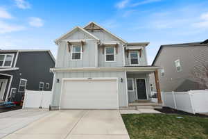 View of front of home featuring a gate, fence, board and batten siding, and concrete driveway