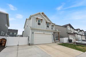 View of front of house featuring fence, an attached garage, board and batten siding, driveway, and a gate