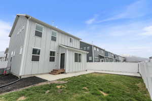 Rear view of house featuring a fenced backyard, board and batten siding, a mountain view, a yard, and a patio area