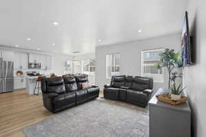 Living room with light wood-type flooring, recessed lighting, and a chandelier