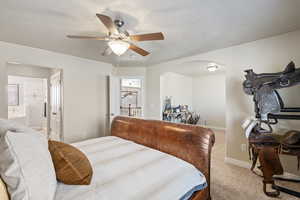 Bedroom featuring ensuite bath, baseboards, arched walkways, ceiling fan, and carpet