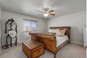 Bedroom with baseboards, a textured ceiling, a ceiling fan, and light colored carpet