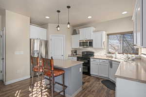 Kitchen with a kitchen breakfast bar, white cabinets, appliances with stainless steel finishes, and dark wood finished floors