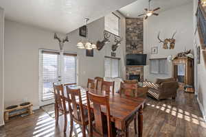 Dining area with baseboards, a textured ceiling, ceiling fan, a fireplace, and wood finished floors