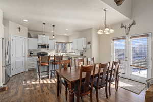 Dining room featuring plenty of natural light, dark wood finished floors, recessed lighting, and an inviting chandelier