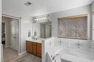 Bathroom with visible vents, vanity, a bath, and tile patterned flooring
