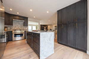 Kitchen with recessed lighting, high end stainless steel range oven, light wood-type flooring, a center island, and tasteful backsplash