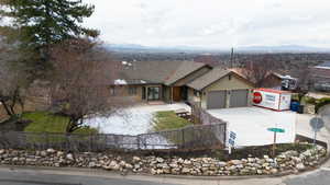 Ranch-style house featuring driveway, fence private yard, an attached garage, a mountain view, and stucco siding