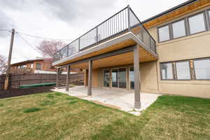 Back of house with a patio area, a balcony, fence, a yard, and stucco siding