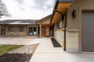 Property entrance featuring french doors, a shingled roof, and stucco siding