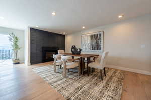 Dining area featuring a fireplace, light wood-style floors, baseboards, and recessed lighting