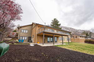 Back of property featuring a patio area, a balcony, central air condition unit, fence, and a yard