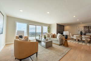 Living room with light wood finished floors, baseboards, and recessed lighting