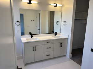 Full bath with baseboards, double vanity, and a sink