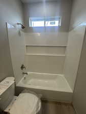 Full bathroom featuring  shower combination, toilet, and wood finished floors